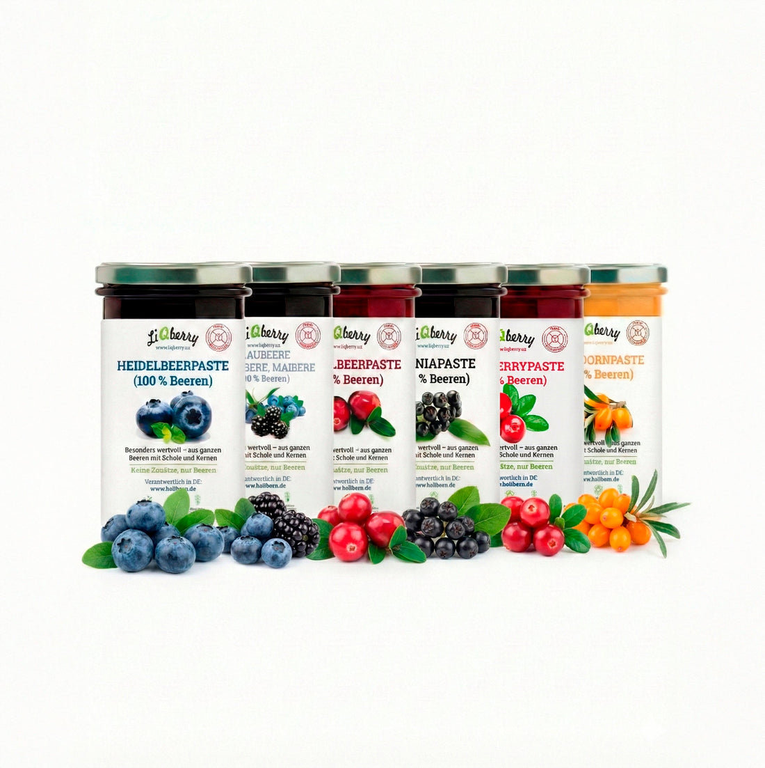 Verschiedene Sorten der Heilkorn Beerenpasten, umgeben von frischen ganzen Früchten wie Sanddorn, Heidelbeeren und Aronia auf einem rustikalen Holztisch